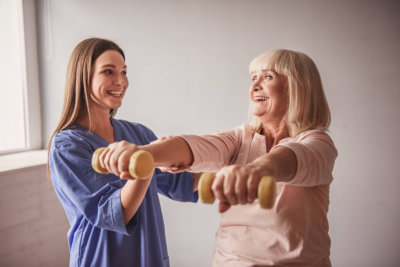 woman helping senior woman do some exercises